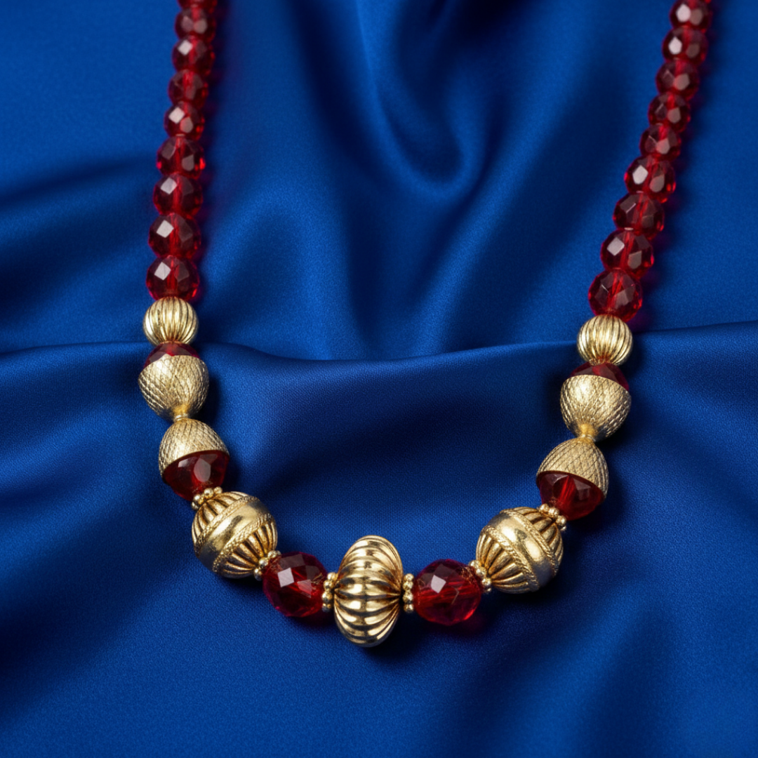 Necklace with red beads and gold accents on a blue fabric background