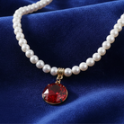 Pearl necklace with a red gemstone pendant on a blue fabric background