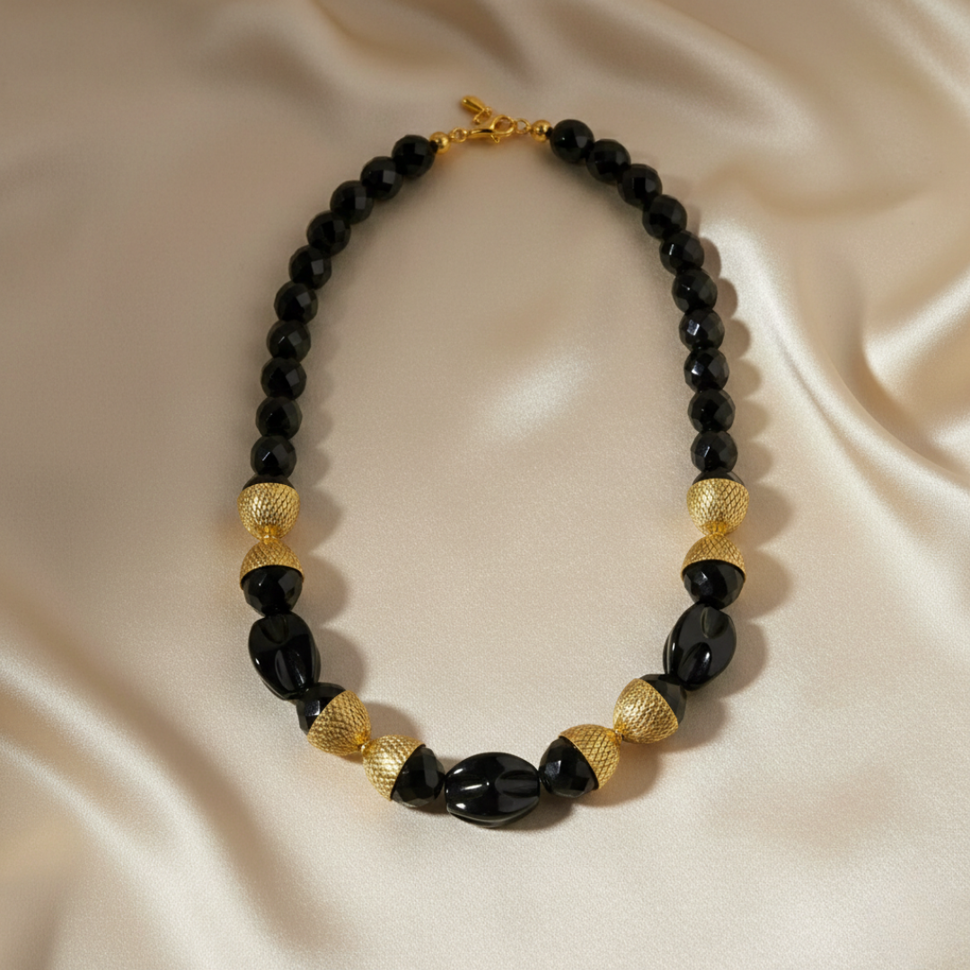 Necklace with black and gold beads on a beige fabric background