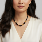 Woman wearing a black and gold beaded necklace against a neutral background