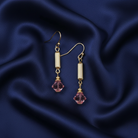 Gold earrings with pink crystals on a blue satin background