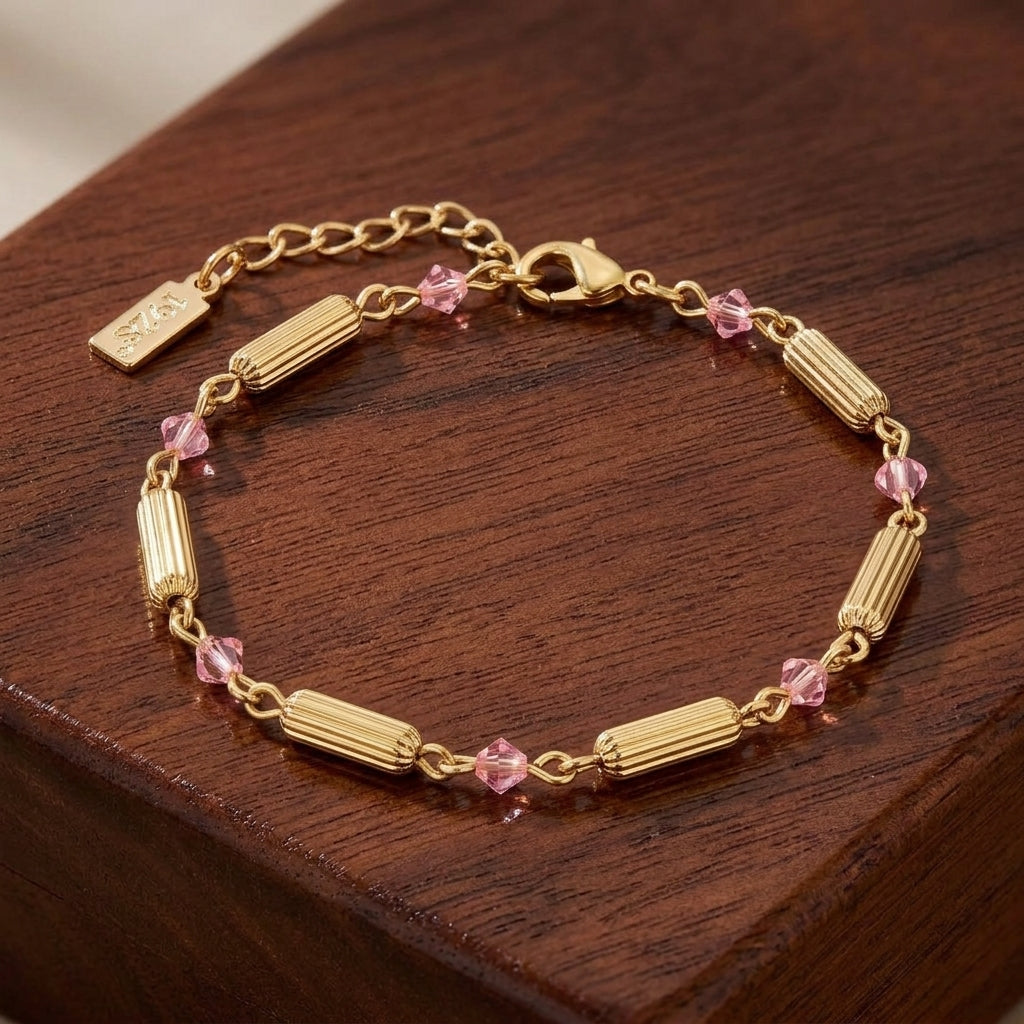 Gold bracelet with pink crystals on a wooden surface
