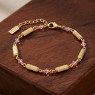 Gold bracelet with pink crystals on a wooden surface
