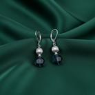 Silver earrings with blue crystals on a green fabric background