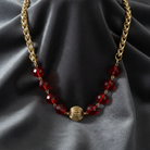 Gold necklace with red beads on a dark fabric background