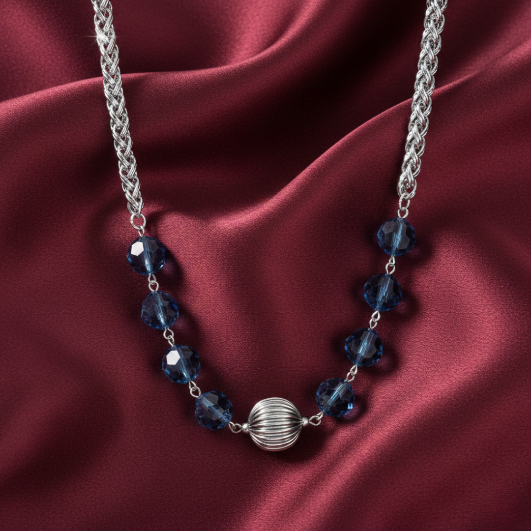 Necklace with blue beads and a silver chain on a red satin background