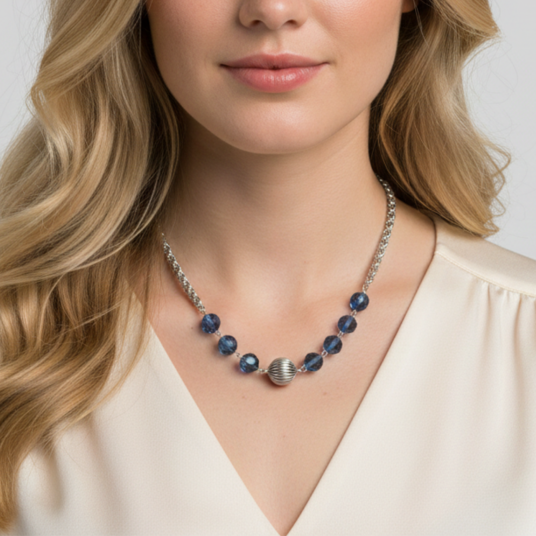 Woman wearing a necklace with blue beads and a silver clasp on a plain background