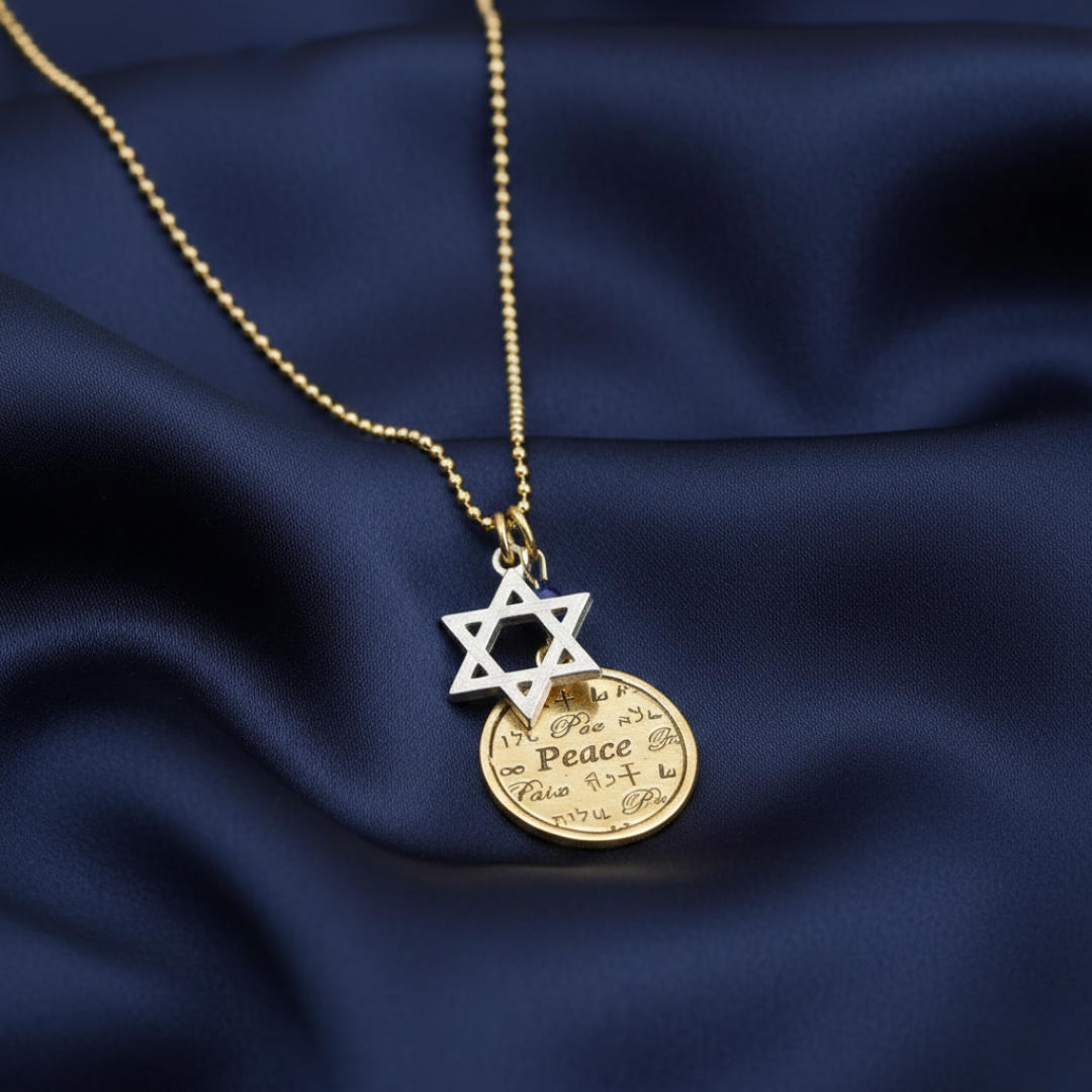 Gold necklace with Star of David and round pendant on a dark blue fabric background
