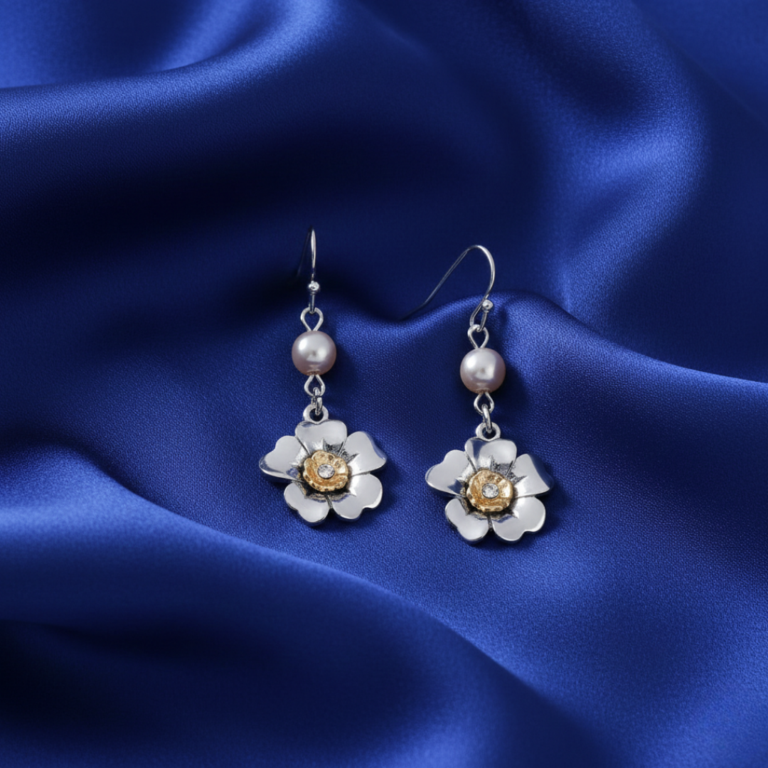 Silver flower-shaped earrings with a central gemstone on a blue satin background
