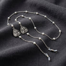 Silver tone Paws & Bones Heart Round Faux Pearl Eyeglass Holder Necklace on dark linen