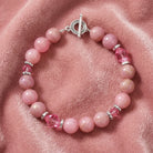 Pink beaded bracelet with silver accents on a pink fabric background