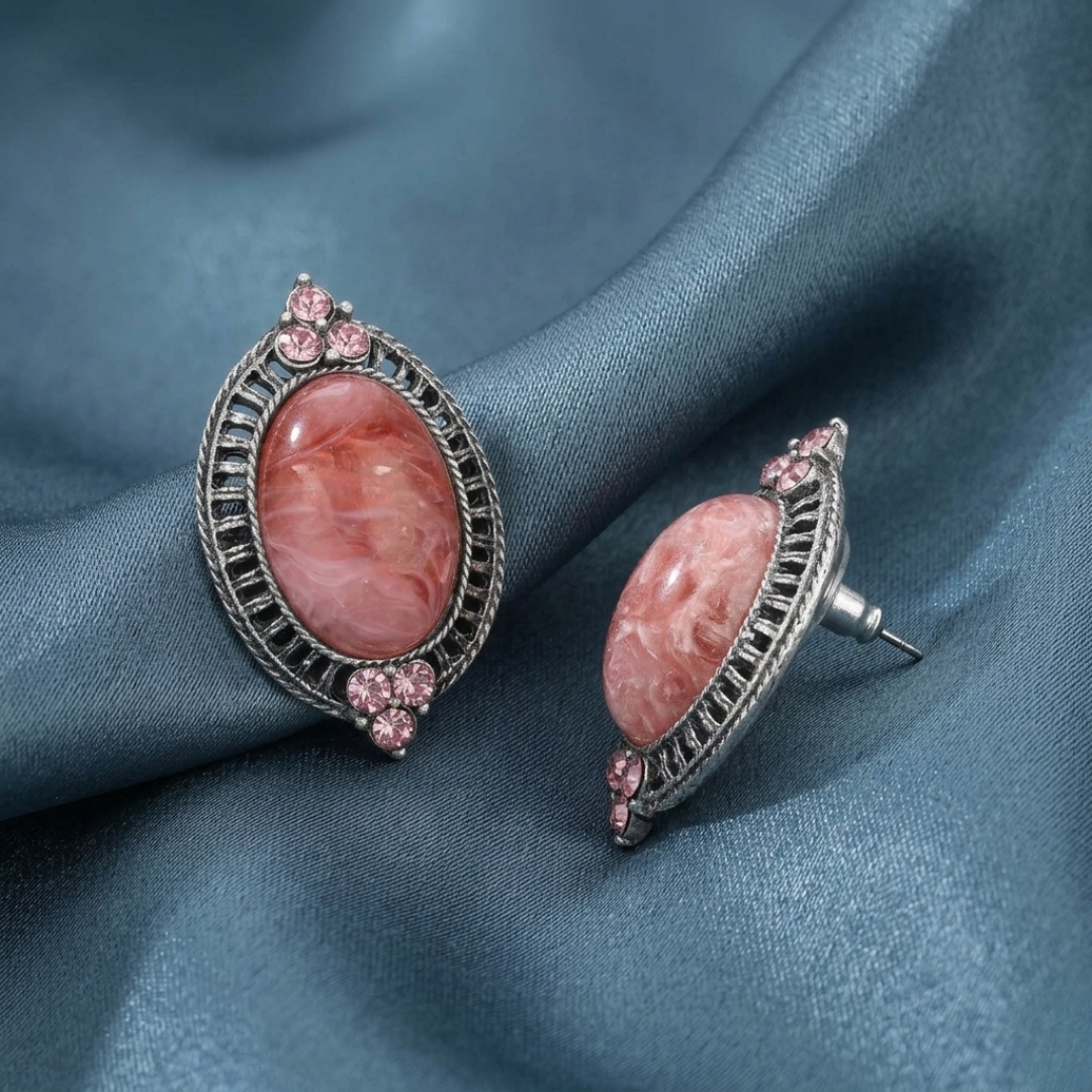 Pair of earrings with pink stones on a blue fabric background