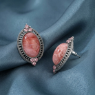 Pair of earrings with pink stones on a blue fabric background