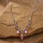 Necklace with pink stones and crystals on a brown stone surface