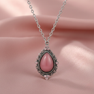 Necklace with a pink teardrop pendant with crystals on a pink background
