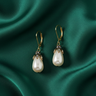 Faux pearl earrings on a green satin background