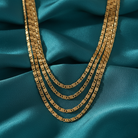 Gold chain necklace on a teal fabric background