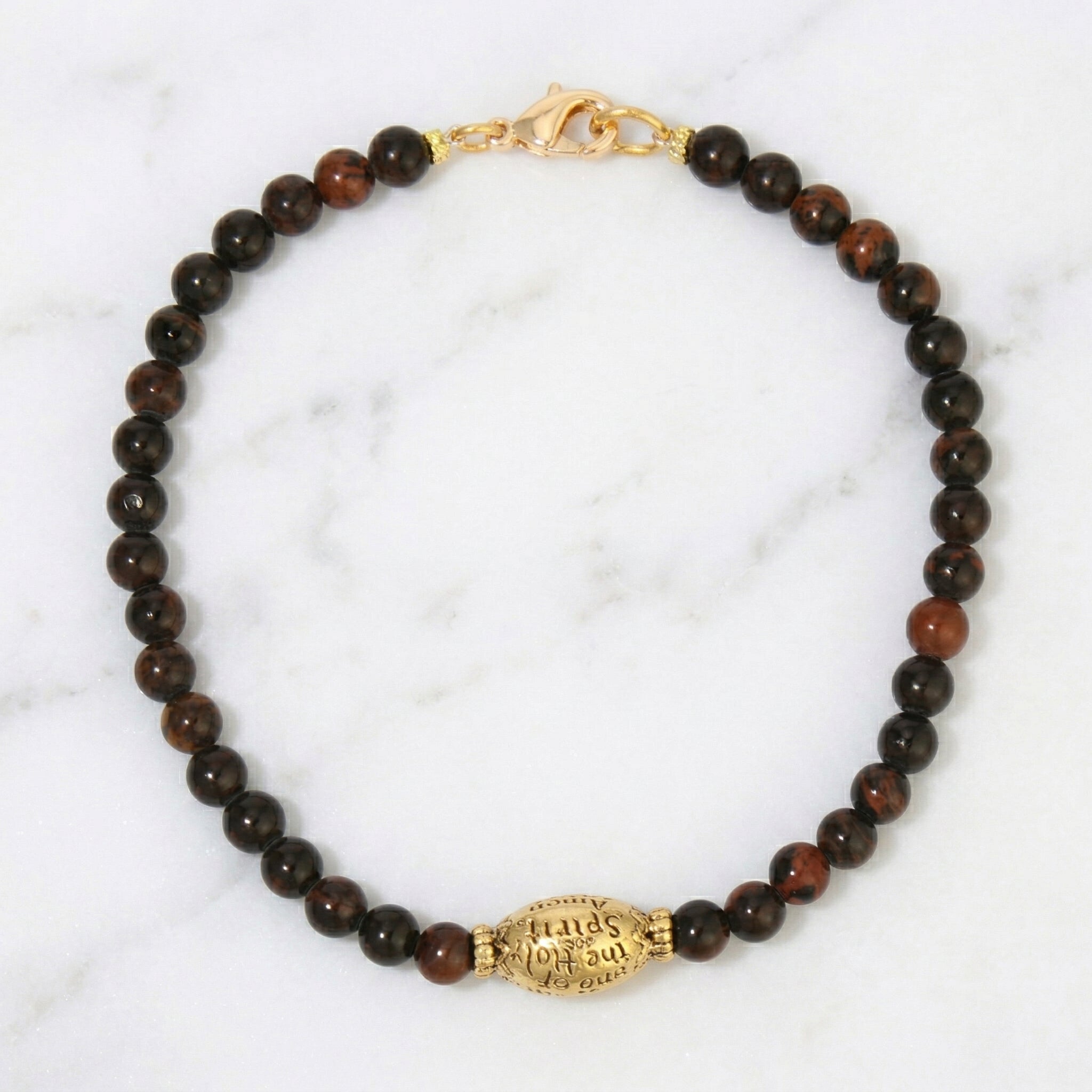 Bracelet with brown beads and gold clasp on a marble background