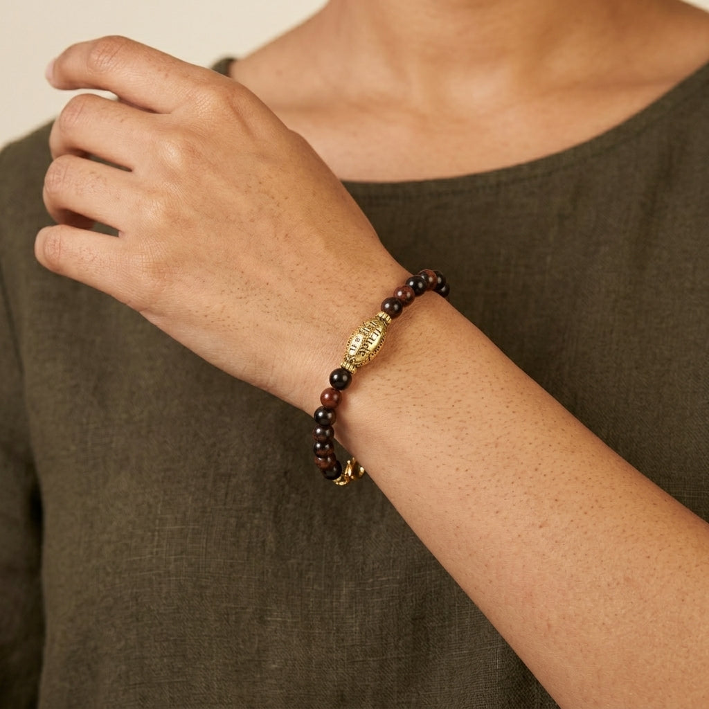 Close-up of a wrist wearing a beaded bracelet with a gold clasp against a neutral background.