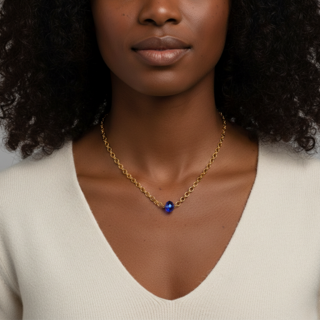 Woman wearing a gold necklace with a blue bead pendant