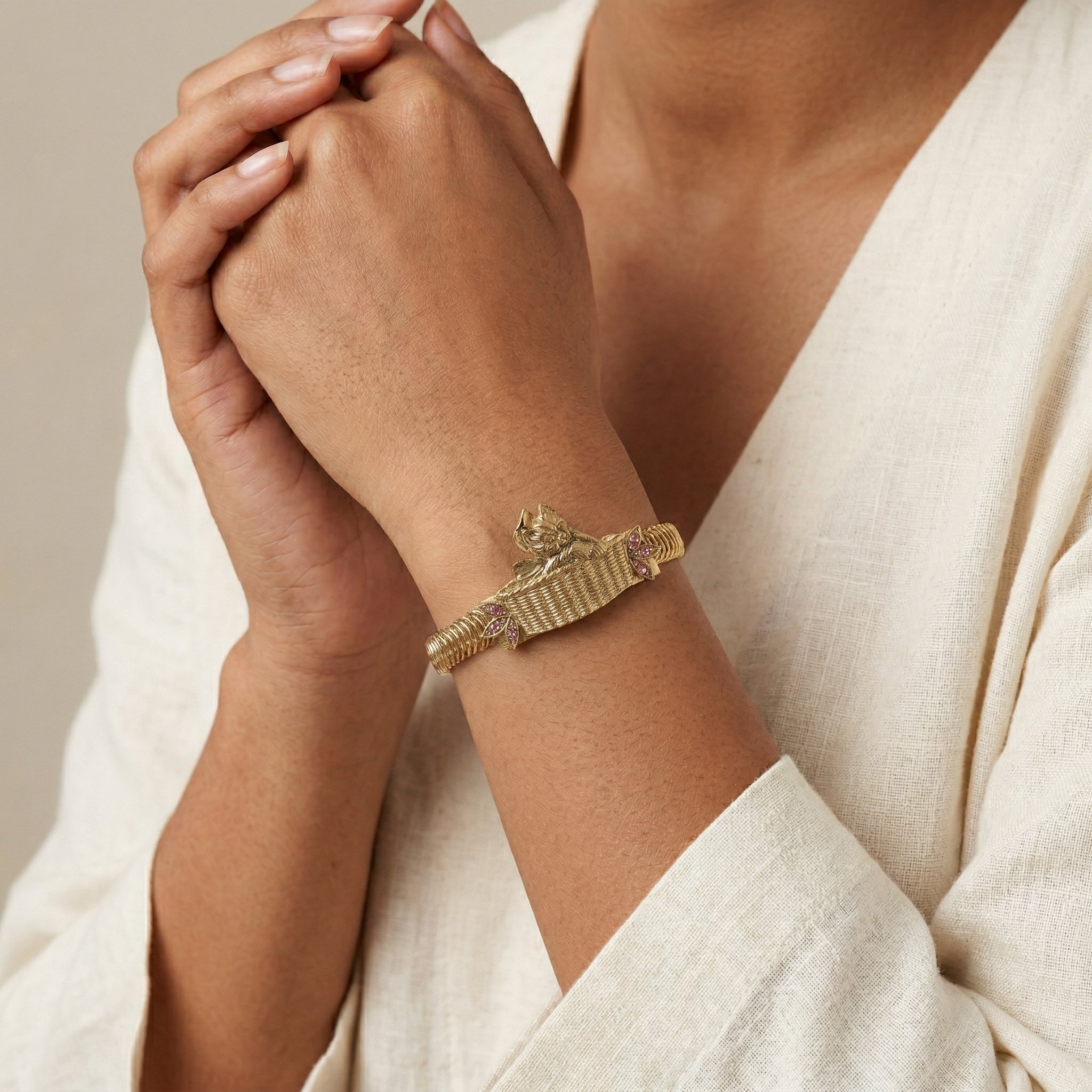 Gold cat bowtie bracelet on a person's wrist with a neutral background