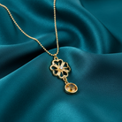 Gold necklace  and a topaz crystal with a floral pendant on teal fabric