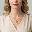 Woman wearing a gold necklace with a floral pendant on a plain background