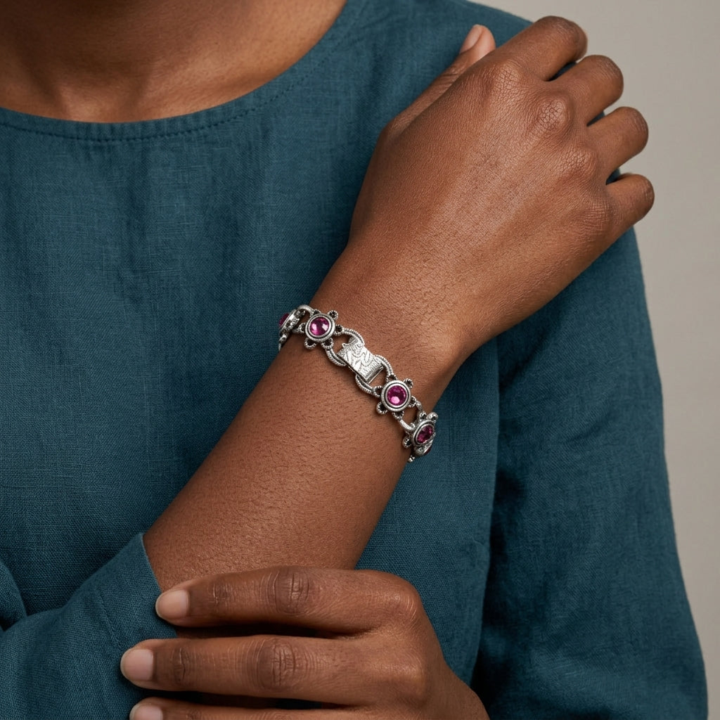 Person wearing a silver bracelet with amethyst stones on a teal garment.