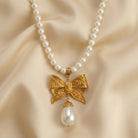 Pearl necklace with a gold bow pendant on a beige fabric background