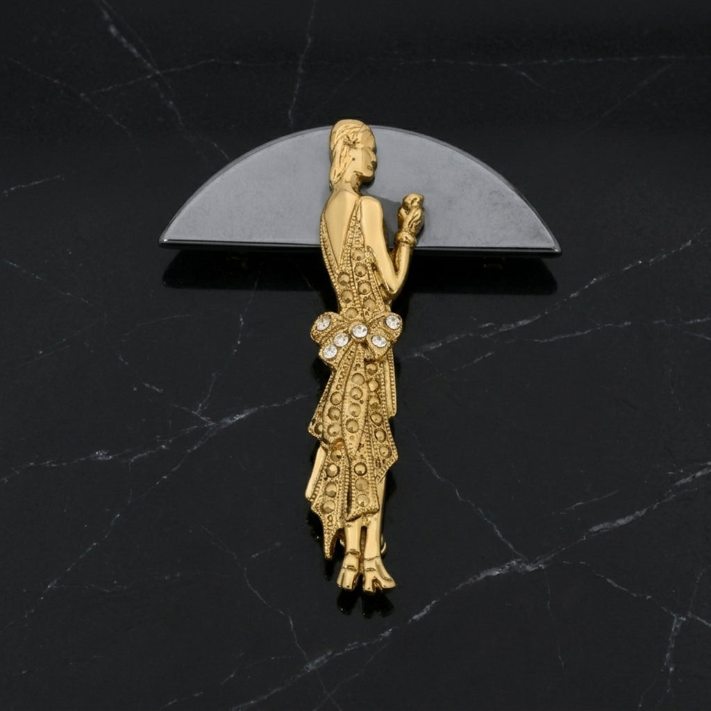 Gold brooch of a 1920s woman on a black marble background