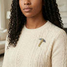Woman wearing a beige sweater with a decorative 1920s style brooch.