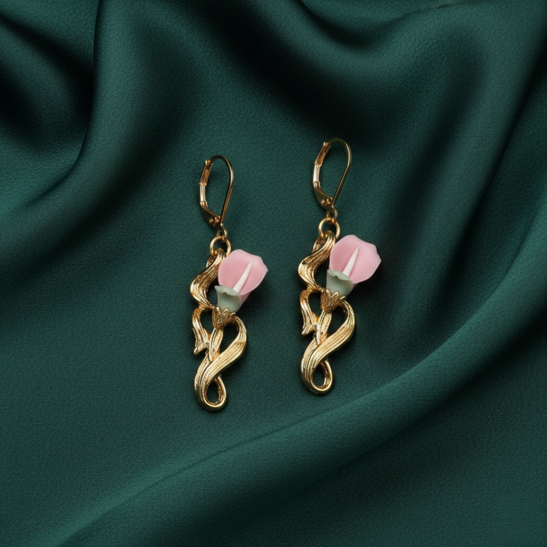 Gold earrings with porcelain roses on a green fabric background
