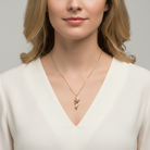Woman wearing a gold necklace with a rose pink floral pendant.