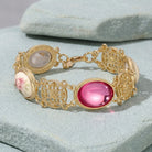 Gold bracelet with pink gemstone on a light stone surface