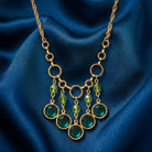 Green Glass Crystal Bib Necklace on a blue fabric background