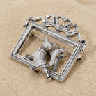 Silver brooch with a cat design on a beige stone surface