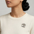 Person wearing a silver cat brooch on a plain background