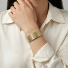 Gold floral bracelet on a person wearing a white shirt