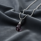 Necklace with a purple crystal pendant on a dark fabric background