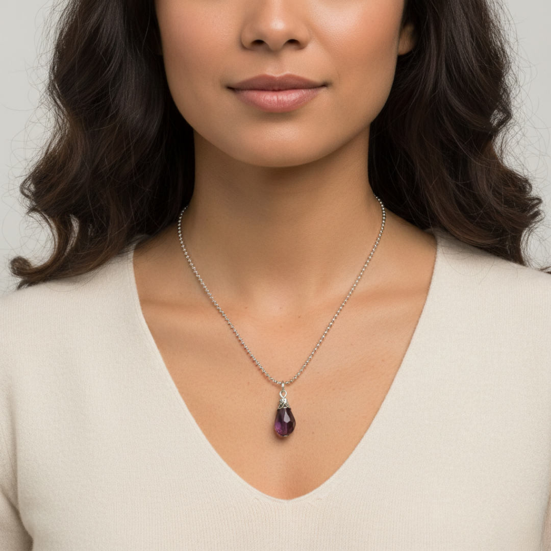 Woman wearing a necklace with a purple pendant against a neutral background