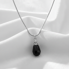 Necklace with a black teardrop pendant on a white fabric background