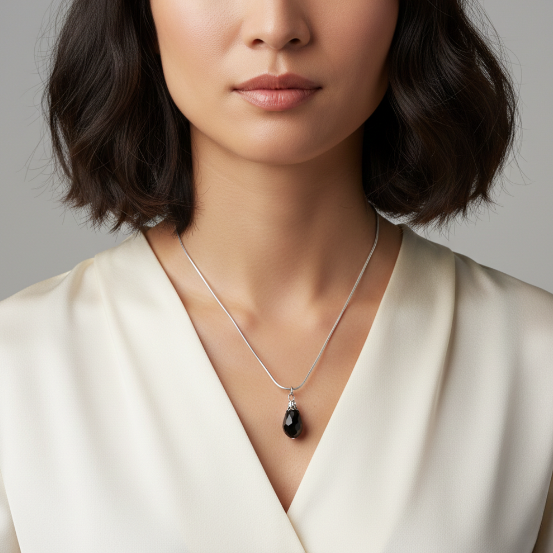 Woman wearing a necklace with a black pendant against a neutral background
