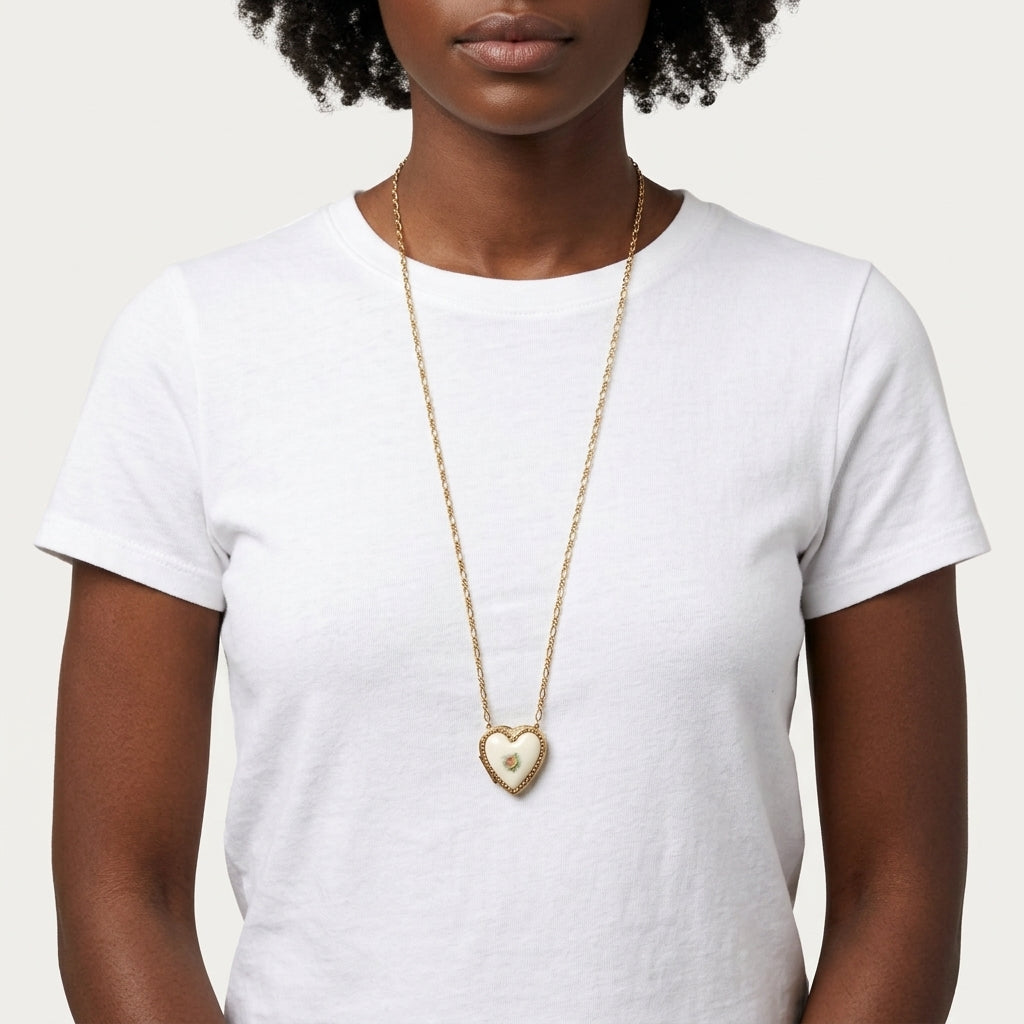 Person wearing a white top with a gold tone Porcelain Heart Rose Motif Pendant Photo Locket Necklace