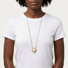 Person wearing a white top with a gold tone Porcelain Heart Rose Motif Pendant Photo Locket Necklace