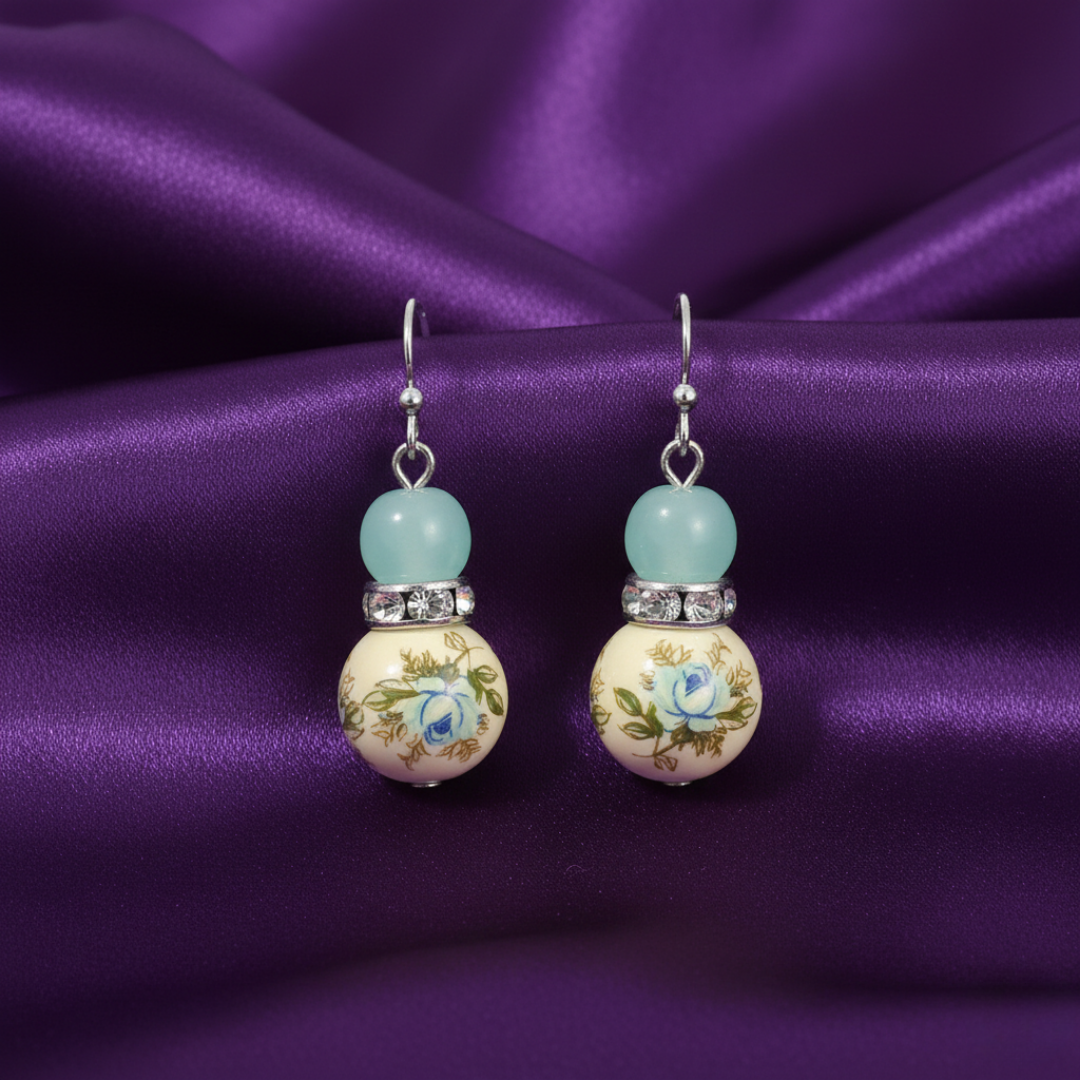 Pair of earrings with floral design on a purple fabric background