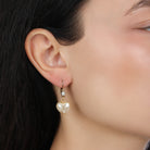 Heart-shaped faux pearl earring worn by a person with dark hair.