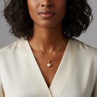 Woman wearing a gold necklace with a heart pendant against a neutral background