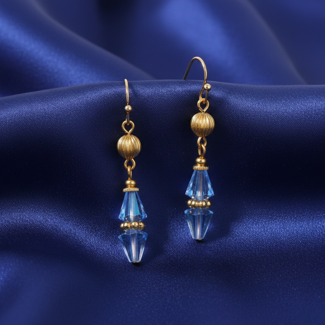 Gold and blue teardrop crystal earrings on a blue satin background