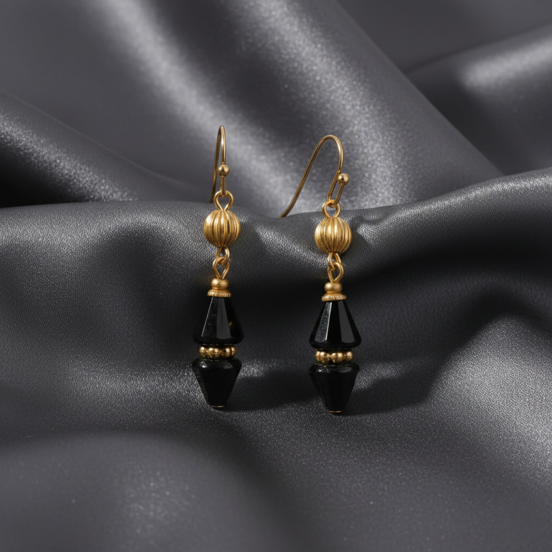 Gold and black crystal teardrop earrings on a dark fabric background