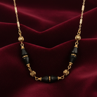 Necklace with gold and black beads on a red fabric background